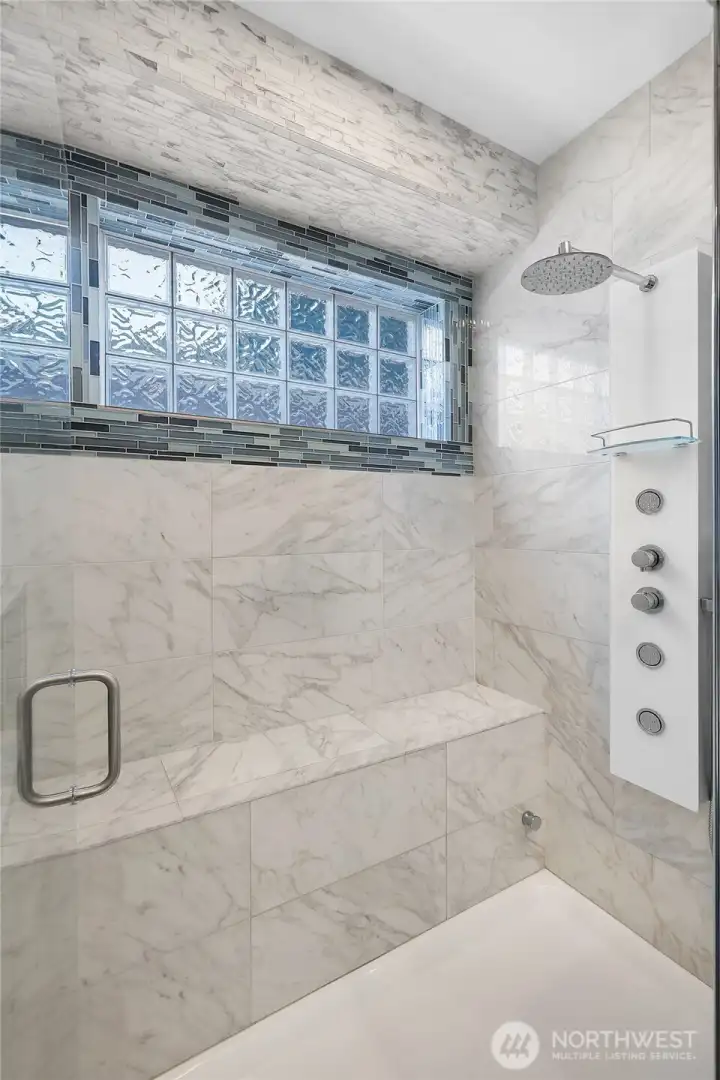 Remodeled primary bathroom featuring a luxurious full-tile steam shower, elegant marble countertops, a double vanity, and a custom-designed closet system—spa-like comfort meets thoughtful design.
