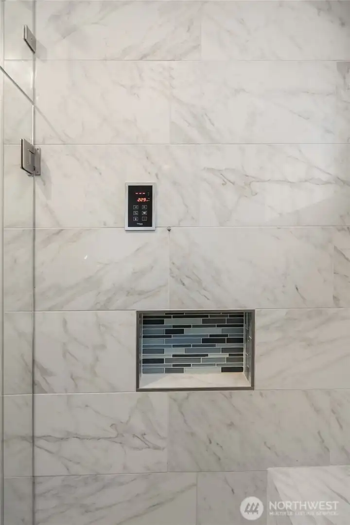 Remodeled primary bathroom featuring a luxurious full-tile steam shower, elegant marble countertops, a double vanity, and a custom-designed closet system—spa-like comfort meets thoughtful design.