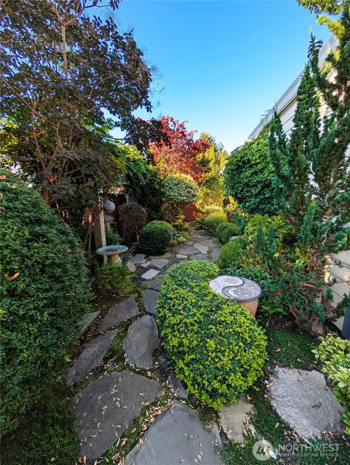 Secret garden–style, fully fenced yard with stunning views of the 12th fairway, featuring a covered Trex deck, custom outdoor lighting, drip and sprinkler systems, and two large arbors, an enchanting outdoor retreat for relaxing or entertaining.