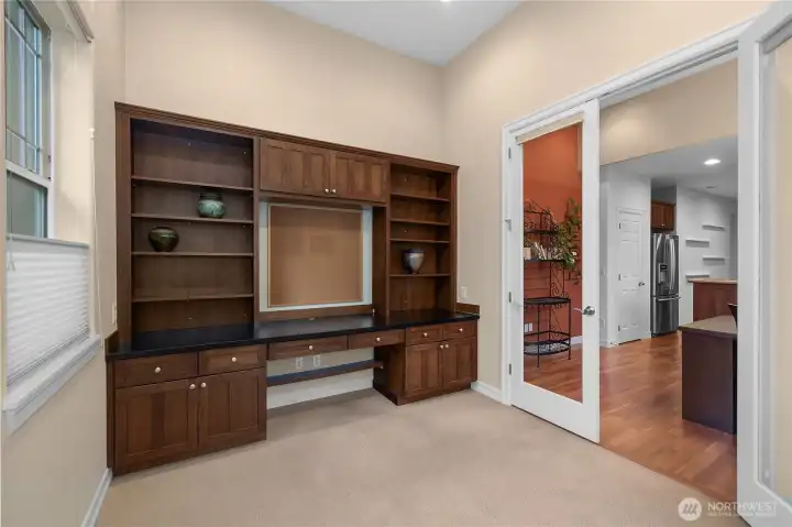 Bright and spacious den/flex space featuring custom built-in cabinets and a desk perfect for a home office, study, or creative workspace.