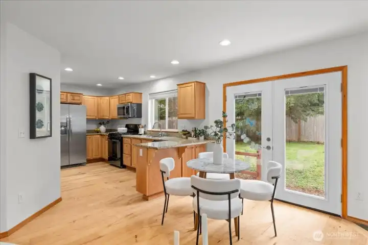 Dining area positioned next to glass doors providing direct access to the backyard. Open-concept design connects the dining space with the kitchen and living area.