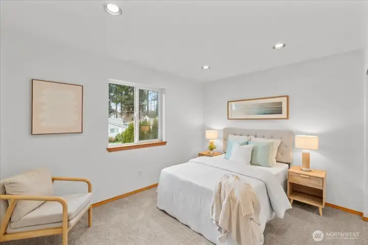 Bedroom with carpeted flooring, recessed lighting, and a large window providing natural light. Space accommodates a bed and additional furnishings.
