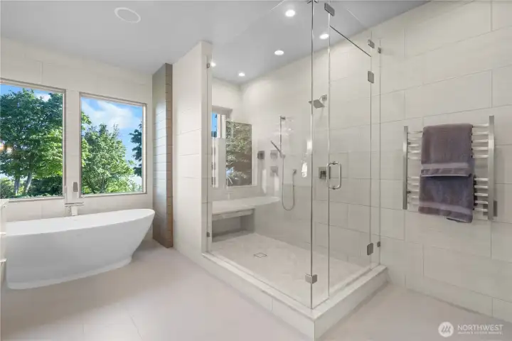 The expansive walk-in shower features dual heads and a frameless glass entry for a modern look.