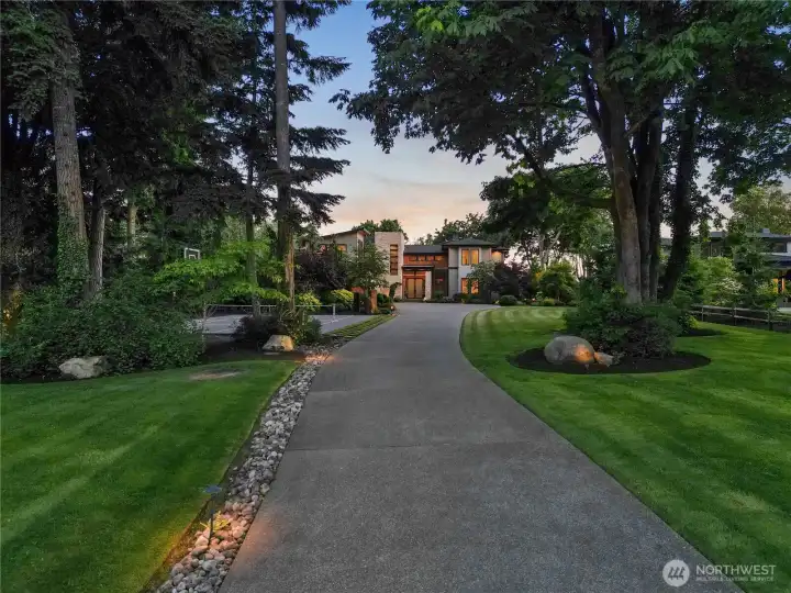 A sprawling, professionally lit driveway provides a dramatic sense of arrival, welcoming you home to this illuminated estate.