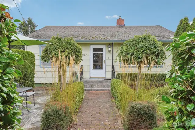 Charming front yard featuring a beautifully landscaped garden with manicured hedges and  trees.