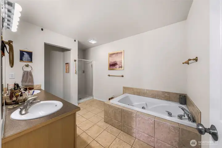 Ensuite primary bath with jetted tub, dual sinks, separate shower and private toilet.