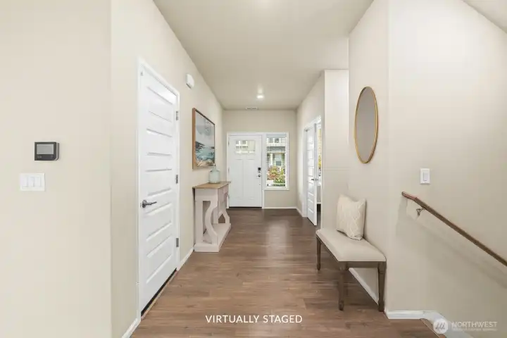 Entryway looking toward the front door, garage to the left. Powder bath and office to the right.