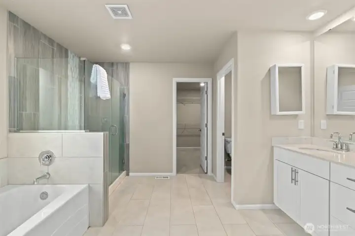 Spacious 5-pc ensuite bathroom with a double vanity, large glass shower and soaking tub, and private toilet room.