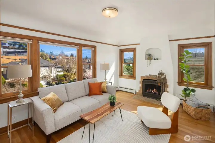 Gorgeous living room with newly finished oak hardwood floor and a inviting wood fireplace, with sweeping views of Cascades, Mt Rainier, the Ship Canal bridge and surrounding areas
