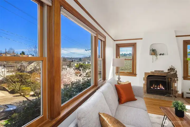 Gorgeous living room with newly finished oak hardwood floor and a inviting wood fireplace, with sweeping views of Cascades, Mt Rainier, the Ship Canal bridge and surrounding areas