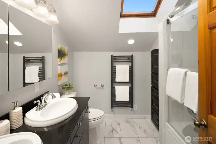 Gorgeously updated primary bathroom with heated marble floors and a towel warmer