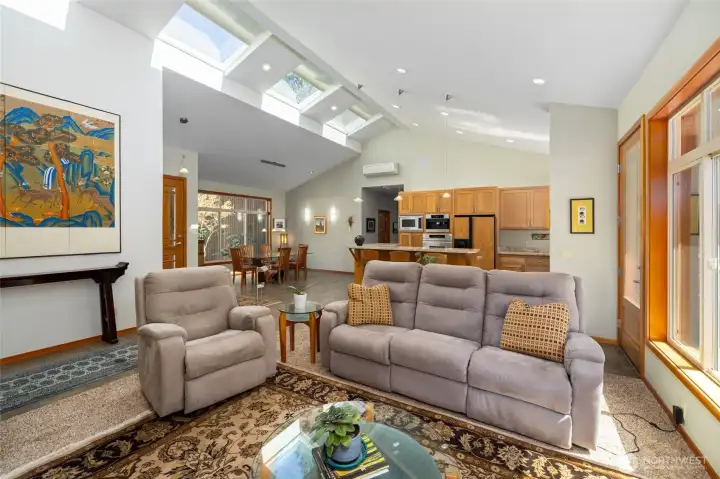 The great room area is flooded with abundant natural light.  Stone tile floors and warm woodwork echo the natural elements visible through the many windows.