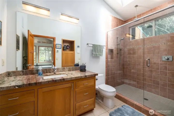 Primary suite #2 private bath, tile floors, granite counters, tiled shower.