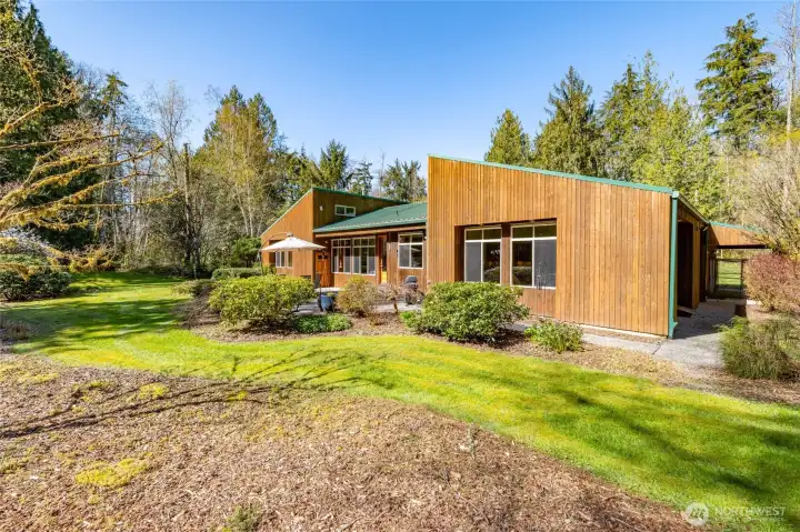 The back of the home, where a patio offers a sunny space for entertaining, or just to relax.  Door on patio leads to a patio storage closet.  Kennel visible along right side of the house.