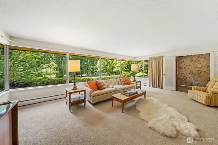 Picture windows bring the outdoors in, showcasing peaceful views of the wooded Bridle Trails setting. This light-filled living room offers timeless Northwest charm and an inviting connection to the property’s private acreage.