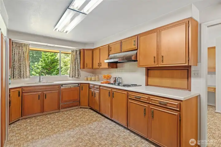 Designed with functionality in mind, this kitchen features extensive cabinetry, generous workspace, and two convenient pass-throughs that keeps all spaces connected. (one pass-through shown here between the kitchen and hobby room.