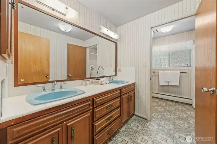 The main bathroom is thoughtfully designed with an extended dual-sink vanity, generous counter space, and abundant storage to keep daily routines organized. The door second door you see here allows for the sinks and vanity space to available while the full bath is in use. Conveniently located near the secondary bedrooms, it comfortably accommodates guests.