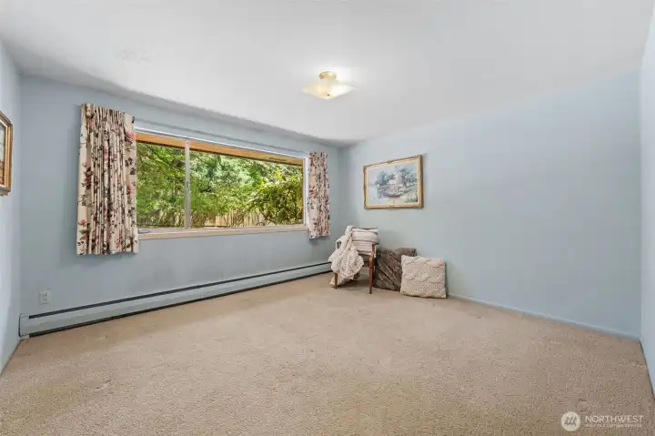 Bedroom Three features a large picture window that fills the room with backyard views and natural light, creating a welcoming space for another bedroom, guests, or a dedicated home office. Its spacious layout provides flexibility for changing needs over the years.