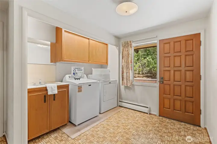 The utility room features a utility sink, upper storage cabinets, and space for a full-size washer and dryer to make everyday tasks more convenient. An exterior door provides easy access to the backyard, adding even more functionality to this well-designed space.