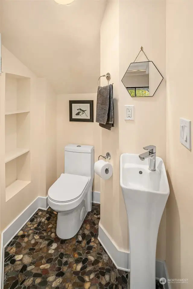 Lower floor has ¾ bath which is split into tow rooms. One room has toilet and faucet with built-in shelving. Rock flooring.