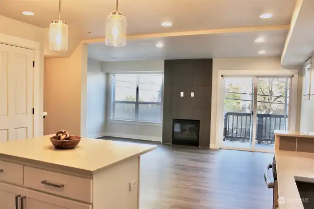 view from kitchen to living room area with gas fireplace and sliding glass door to the deck