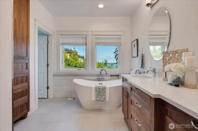 Heated tile floors, water closet with bidet, custom vanity, linen storage, and walk-in shower