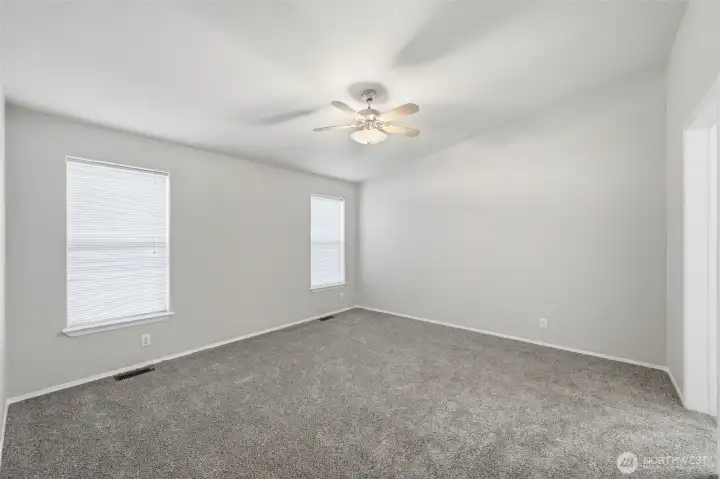 Spacious primary bedroom with new carpet.