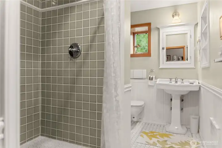 The bathroom has beautiful tile work and mainscotting.