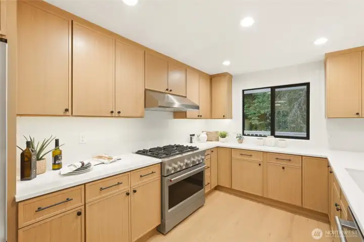 Warm white oak cabinetry, updated appliances, and timeless finishes create a standout kitchen.