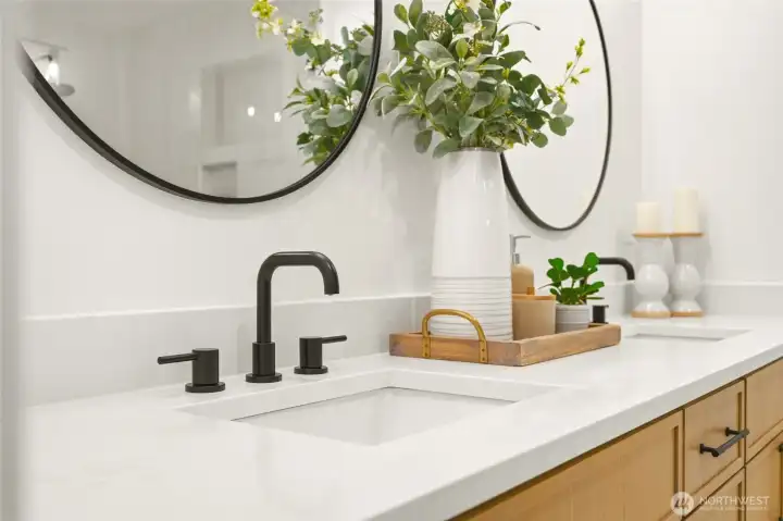 Close-up of the primary bath vanity showcasing quartz surfaces, black fixtures, and elevated detail.