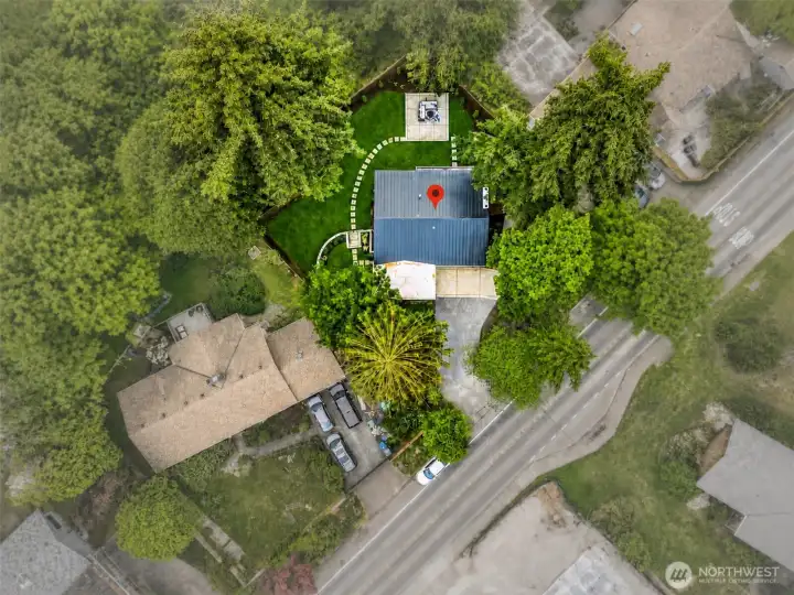 Aerial perspective highlights the property’s large lot, circular driveway, and private setting surrounded by greenery.