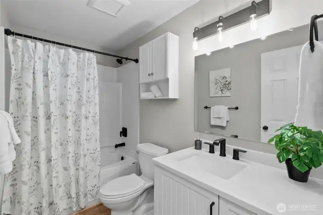 Pretty Hall Bathroom with quartz topped vanity, large mirror, toilet and tub/shower combo!