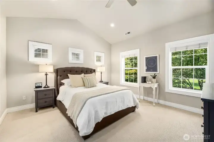 Primary bedroom with vaulted ceilings and views of the park