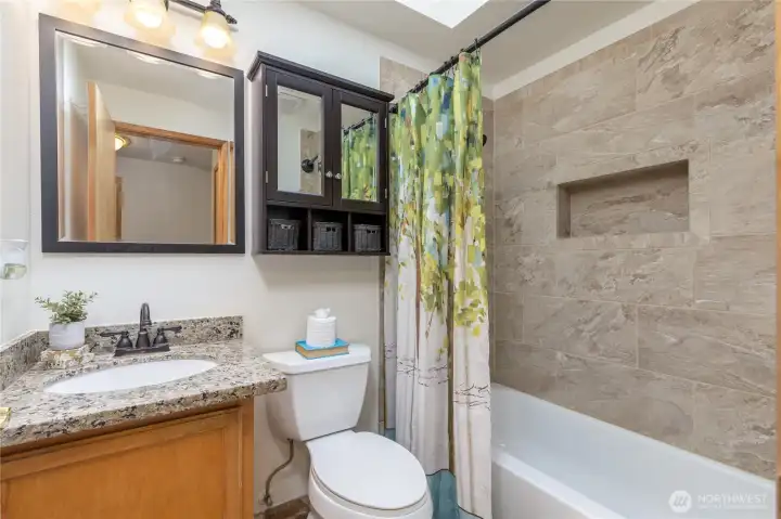Full hall bath with granite counter, tiled tub surround
