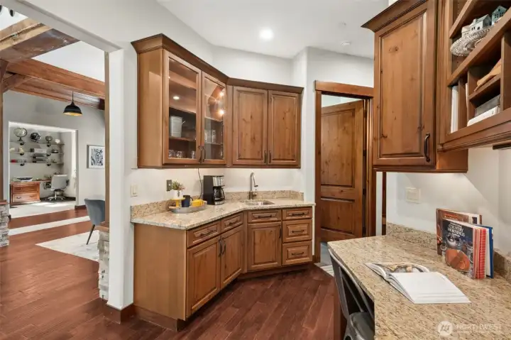 Just off the main living areas, a thoughtfully designed wet bar and command center offers granite surfaces, ample cabinetry, and a prep sink—ideal for morning coffee, homework station, or hosting with ease.