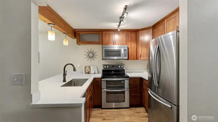 The full kitchen has stainless steel appliances, a farmhouse style sink, and a double oven.