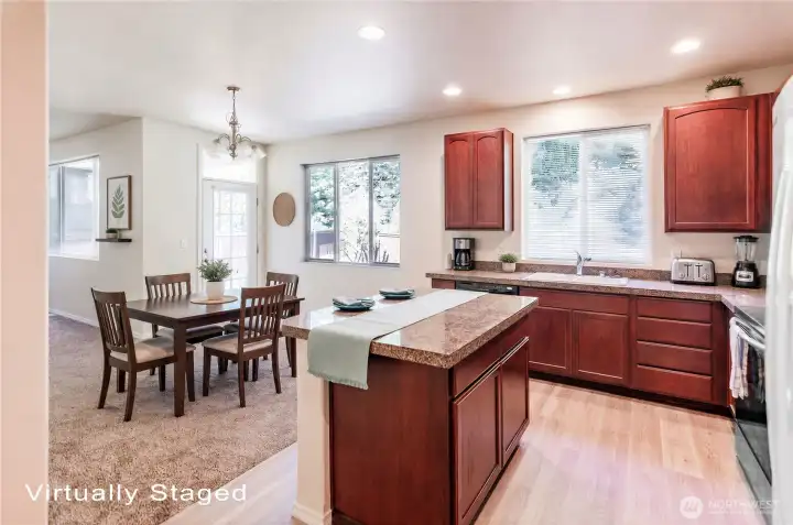 Open kitchen has brand new vinyl plank flooring and rich cabinetry.