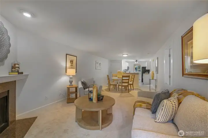 An elongated sightline from fireplace to kitchen emphasizes the open-concept design, fresh interior paint, and new carpet that together create a bright, move-in-ready backdrop.