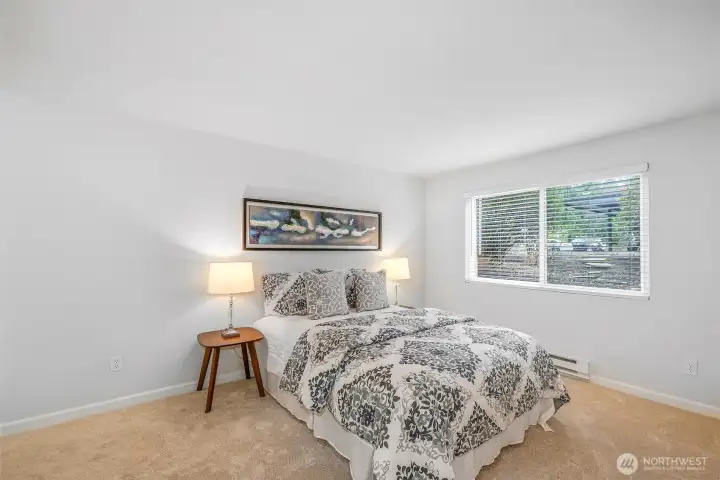 The primary bedroom offers plush new carpet, a wide picture window for afternoon light, and direct access to a full, updated bath—one of two refreshed bathrooms in this two-bed home.