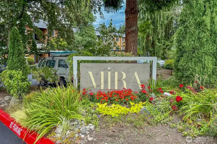 A welcoming monument sign, framed by vibrant plantings, marks the entrance to the Mira community.