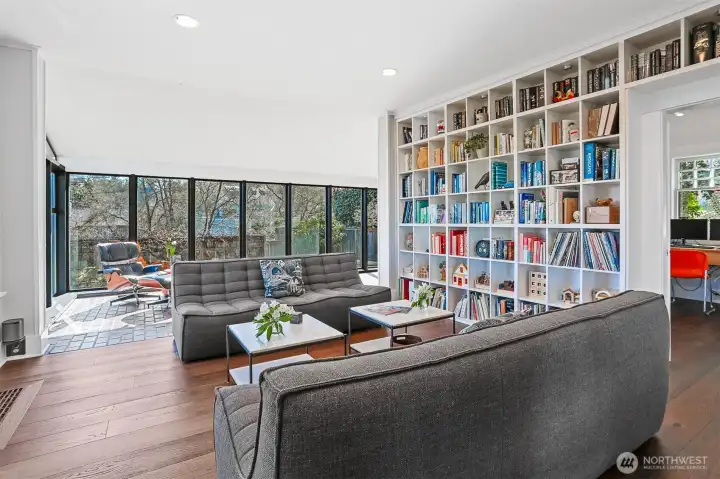 The stately living room features handsome wide plank engineered hardwood floors and floor-to-ceiling bookcases.