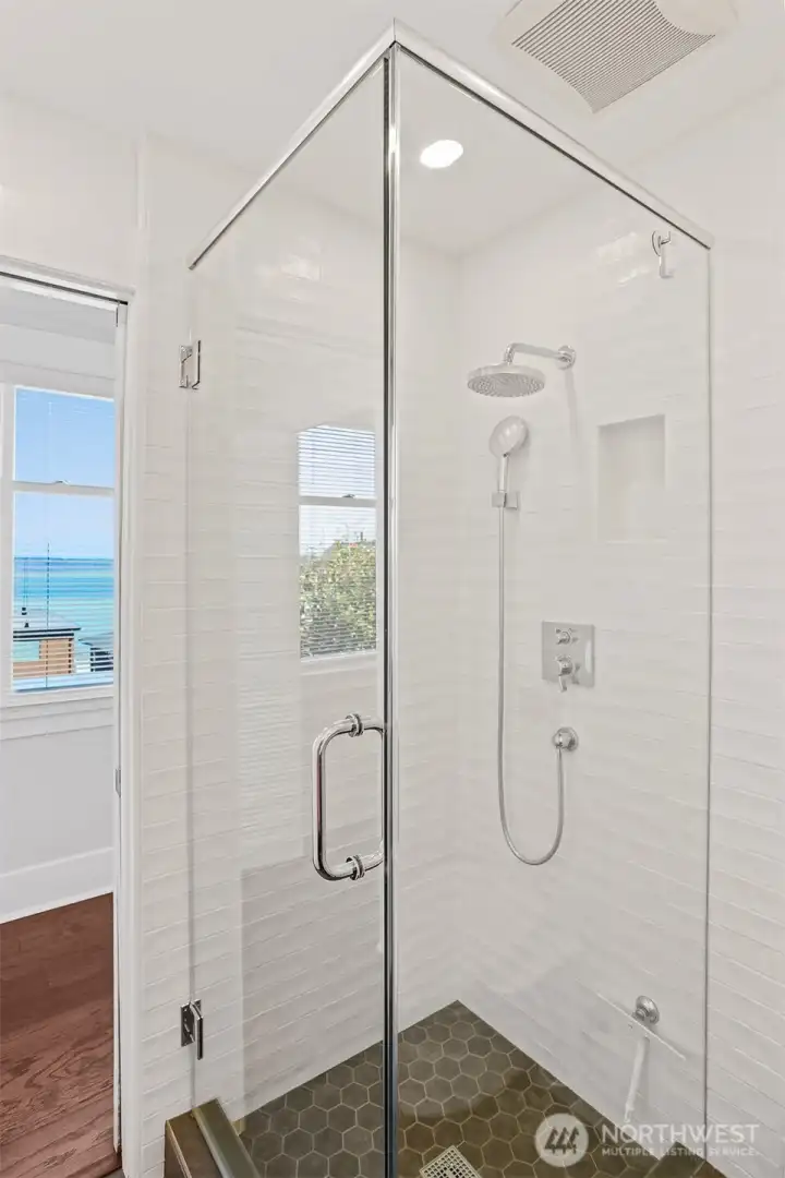Primary suite shower with beautiful modern tilework and glass enclosure.