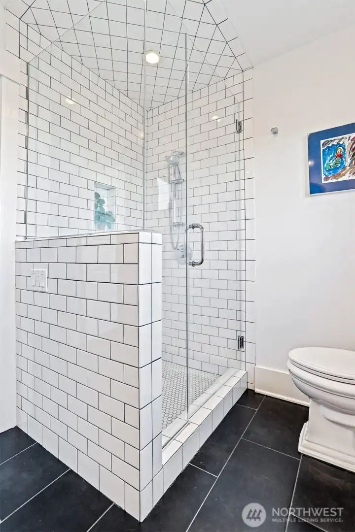 Modern shower with clean subway tiles and glass enclosure.