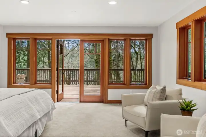 Primary bedroom with direct access to the deck and wooded views