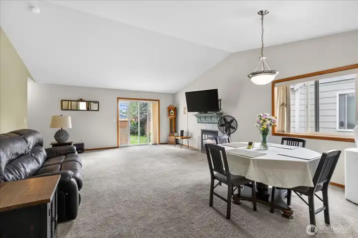 Enter into the great room with vaulted ceilings, gas fireplace, slider to the back patio, and dining area.