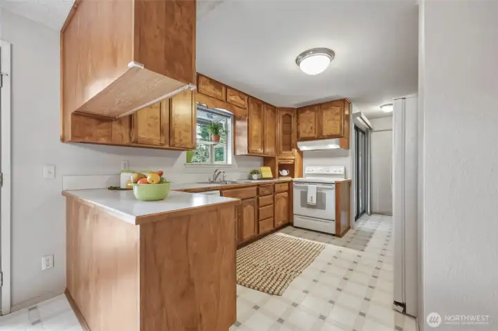 Beautiful solid wood cabinetry in more of a maple brown tone is loaded with features that make everyday cooking easier, including pull-out shelves, two Lazy Susans, pull-out cutting boards, custom baking sheet storage, a built-in spice rack and a clever appliance garage that keeps countertops looking neat while your favorite small appliances stay within easy reach. The garden window above the sink is just waiting for fresh herbs, while the sliding glass door offers quick access to the deck for outdoor dining and barbecues. Even better, all kitchen appliances stay with the home, so you're ready to settle in from day one. Beautiful solid wood cabinetry in more of a maple brown tone is loaded with features that make everyday cooking easier, including pull-out shelves, two Lazy Susans, pull-out cutting boards, custom baking sheet storage, a built-in spice rack and a clever appliance garage that keeps countertops looking neat while your favorite small appliances stay within easy reach. The garden window above the sink is just waiting for fresh herbs, while the sliding glass door offers quick access to the deck for outdoor dining and barbecues. Even better, all kitchen appliances stay with the home, so you're ready to settle in from day one.