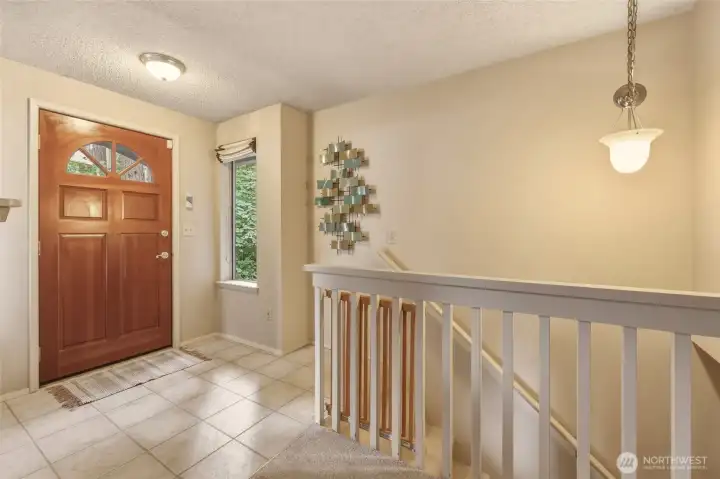 Let's head back down the hallway to the staircase. The solid wood front door with its charming sunburst divided-glass window is one of those original details that gives the home so much personality, while matching sidelights dressed with custom Roman shades welcome in beautiful natural light without giving up privacy. Durable vinyl flooring stands up beautifully to muddy boots, wet dogs and everyday life, and the staircase to the daylight basement keeps the home's two living areas comfortably connected. Let's head back down the hallway to the staircase. The solid wood front door with its charming sunburst divided-glass window is one of those original details that gives the home so much personality, while matching sidelights dressed with custom Roman shades welcome in beautiful natural light without giving up privacy. Durable vinyl flooring stands up beautifully to muddy boots, wet dogs and everyday life, and the staircase to the daylight basement keeps the home's two living areas comfortably connected.