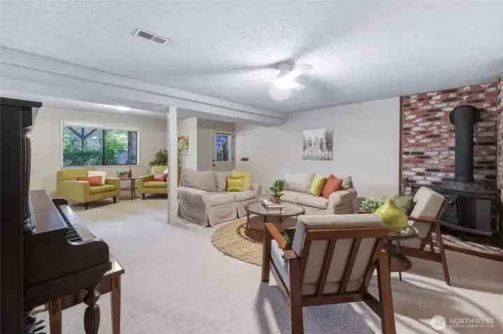 If your upstairs is for gathering, this daylight basement family room is for spreading out. There's room here for movie marathons, game nights, a pool table, exercise equipment, hobbies or all of the above...and you'll probably still have space left over. Oversized picture windows and a windowed exterior door keep the room feeling bright and connected to the backyard, while the corner wood stove and original brick hearth add another warm mid-century nod. A NEW ceiling fan with customizable LED lighting keeps the space comfortable year-round. The antique piano may also stay with the home if the buyer would enjoy giving it its next chapter. If your upstairs is for gathering, this daylight basement family room is for spreading out. There's room here for movie marathons, game nights, a pool table, exercise equipment, hobbies or all of the above...and you'll probably still have space left over. Oversized picture windows and a windowed exterior door keep the room feeling bright and connected to the backyard, while the corner wood stove and original brick hearth add another warm mid-century nod. A NEW ceiling fan with customizable LED lighting keeps the space comfortable year-round. The antique piano may also stay with the home if the buyer would enjoy giving it its next chapter.