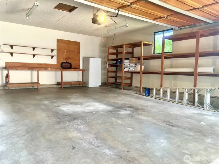 This oversized 2-car garage was designed for more than just parking. Natural light pours in through the large window overlooking mature greenery, making projects a whole lot more enjoyable than working in a dark garage. Solid wood built-in shelving, a generous workbench and additional wall shelving provide exceptional organization for tools, hobbies and weekend projects. The automatic garage door opener is already in place, and if you'd like, the upright freezer can stay with the home, giving you even more everyday convenience. This oversized 2-car garage was designed for more than just parking. Natural light pours in through the large window overlooking mature greenery, making projects a whole lot more enjoyable than working in a dark garage. Solid wood built-in shelving, a generous workbench and additional wall shelving provide exceptional organization for tools, hobbies and weekend projects. The automatic garage door opener is already in place, and if you'd like, the upright freezer can stay with the home, giving you even more everyday convenience.