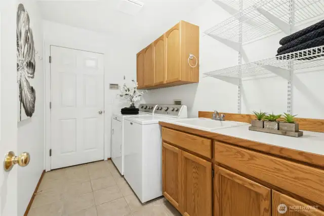 Utility room with a sink, cabinets and counter top. Door leads out to the large 3-car garage.